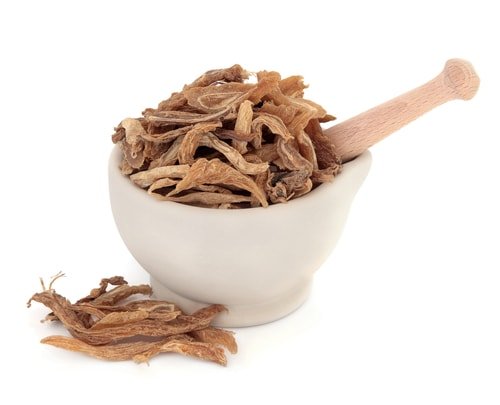 Dried Chinese herbs in a white mortar with a pestle