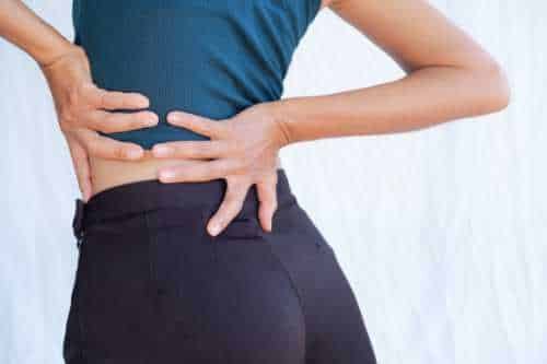 Person pressing both hands into the lower back