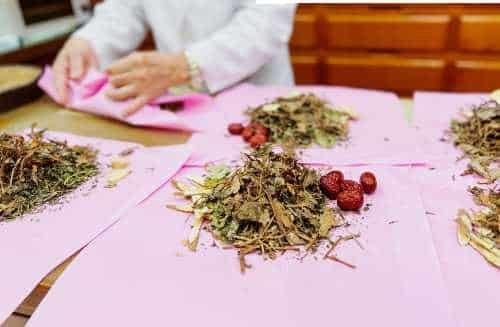 Practitioner weighing out herbs onto paper for a formula