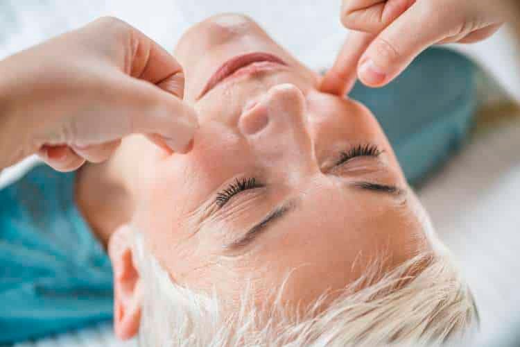 Therapist massaging points on a woman’s face