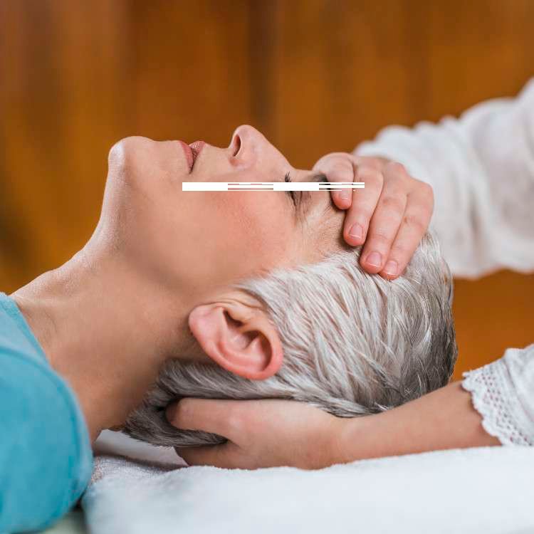 Therapist massaging an older woman’s head and temples