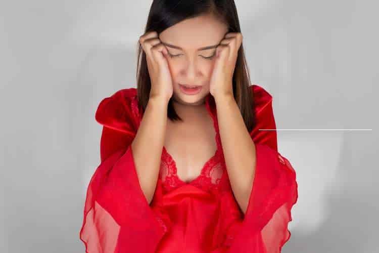 Woman in red holding her head in distress