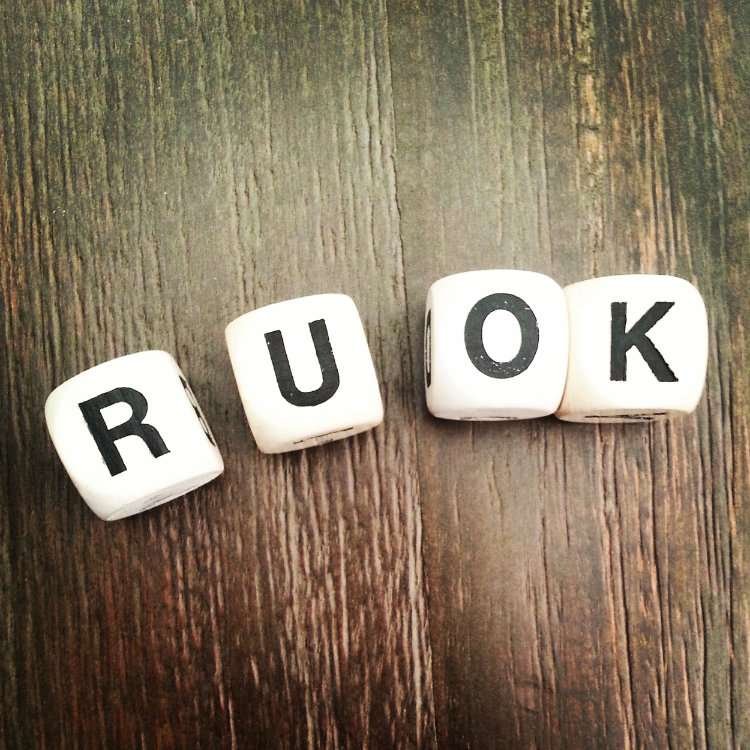 Letter tiles spelling R U OK on a wooden table