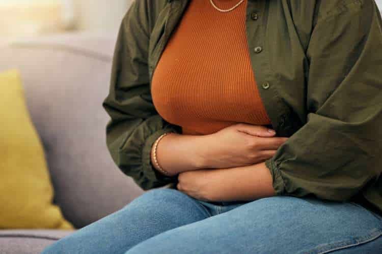 Woman on a sofa holding her stomach