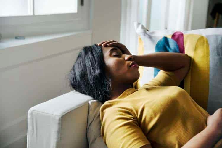 Woman lying on a sofa with a hand on her forehead