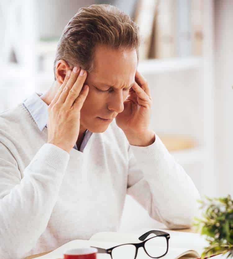 Man at a desk holding his head