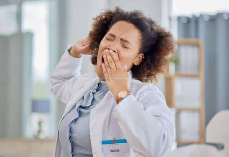 Woman in a lab coat yawning