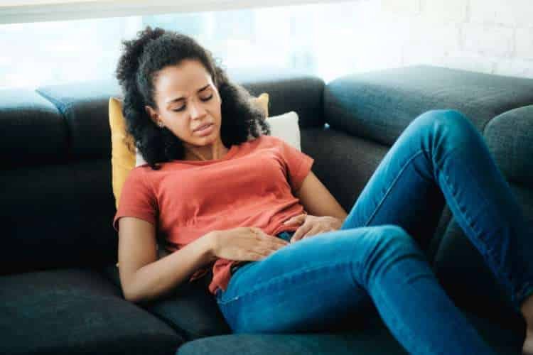 Woman on a sofa holding her stomach