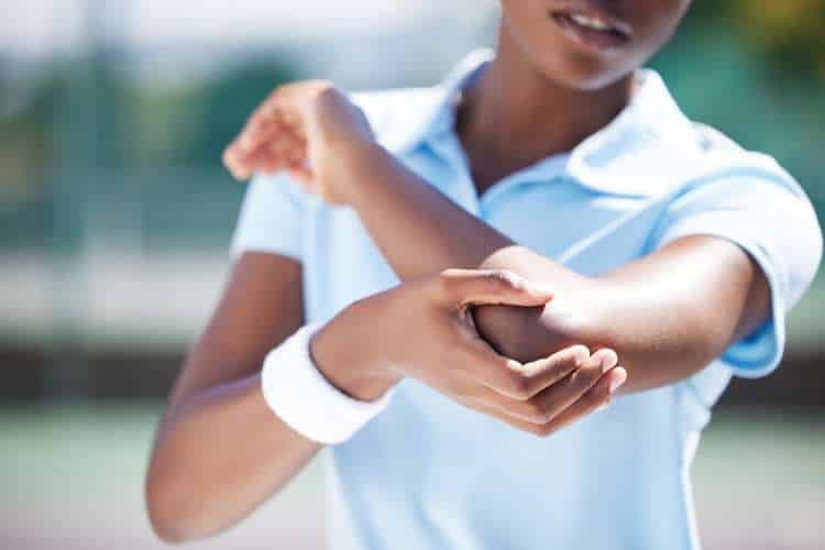 Person in a tennis shirt holding their elbow